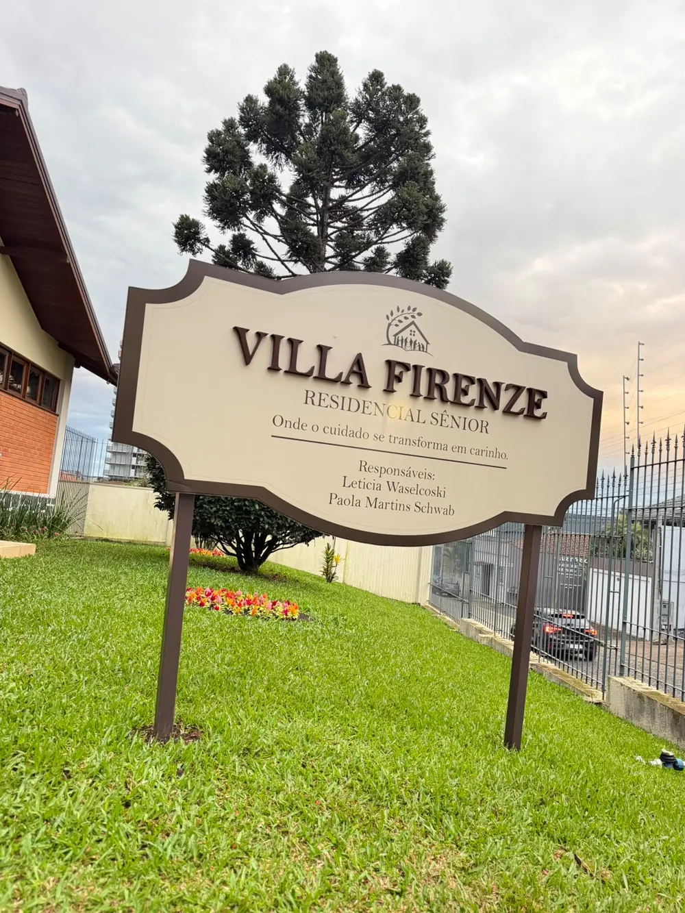 Placa na entrada do Villa Firenze, no gramado, com a frase Onde o cuidado se transforma em carinho e o nome das responsáveis.