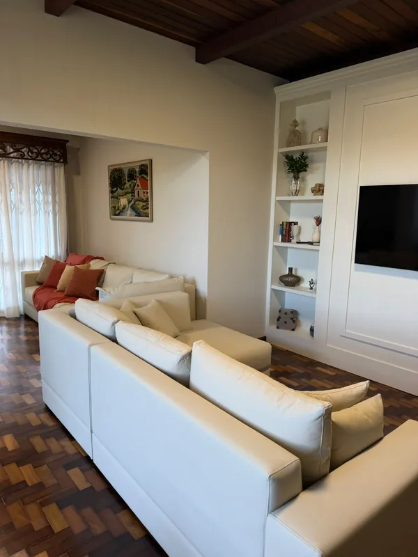 Sala de convivência do Villa Firenze, com sofá em L, estante planejada e televisão.